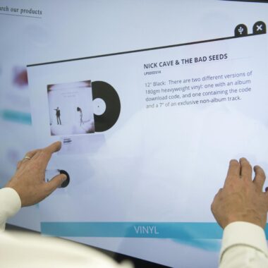 A person using a touchscreen to browse vinyl record information for Nick Cave & The Bad Seeds.