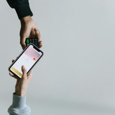 Hands using smartphone and terminal for cashless payment, showcasing modern transaction methods.