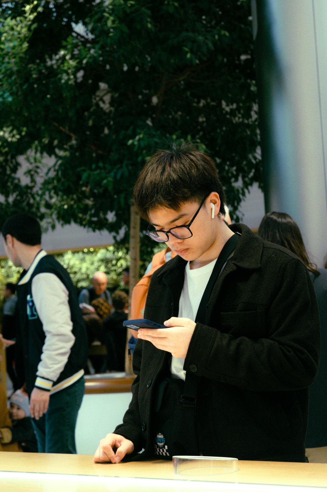Young man engrossed in smartphone shopping experience in New York tech store.